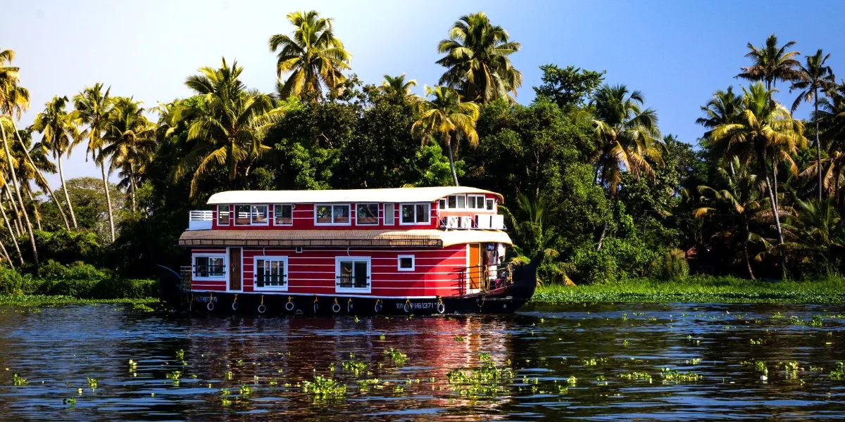 A traditional houseboat drifting through the palm-lined Alleppey backwaters in Kerala
