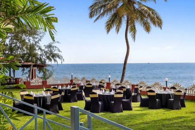 Banquet tables dressed for a gala dinner on a palm-fringed lawn above the sea in Goa