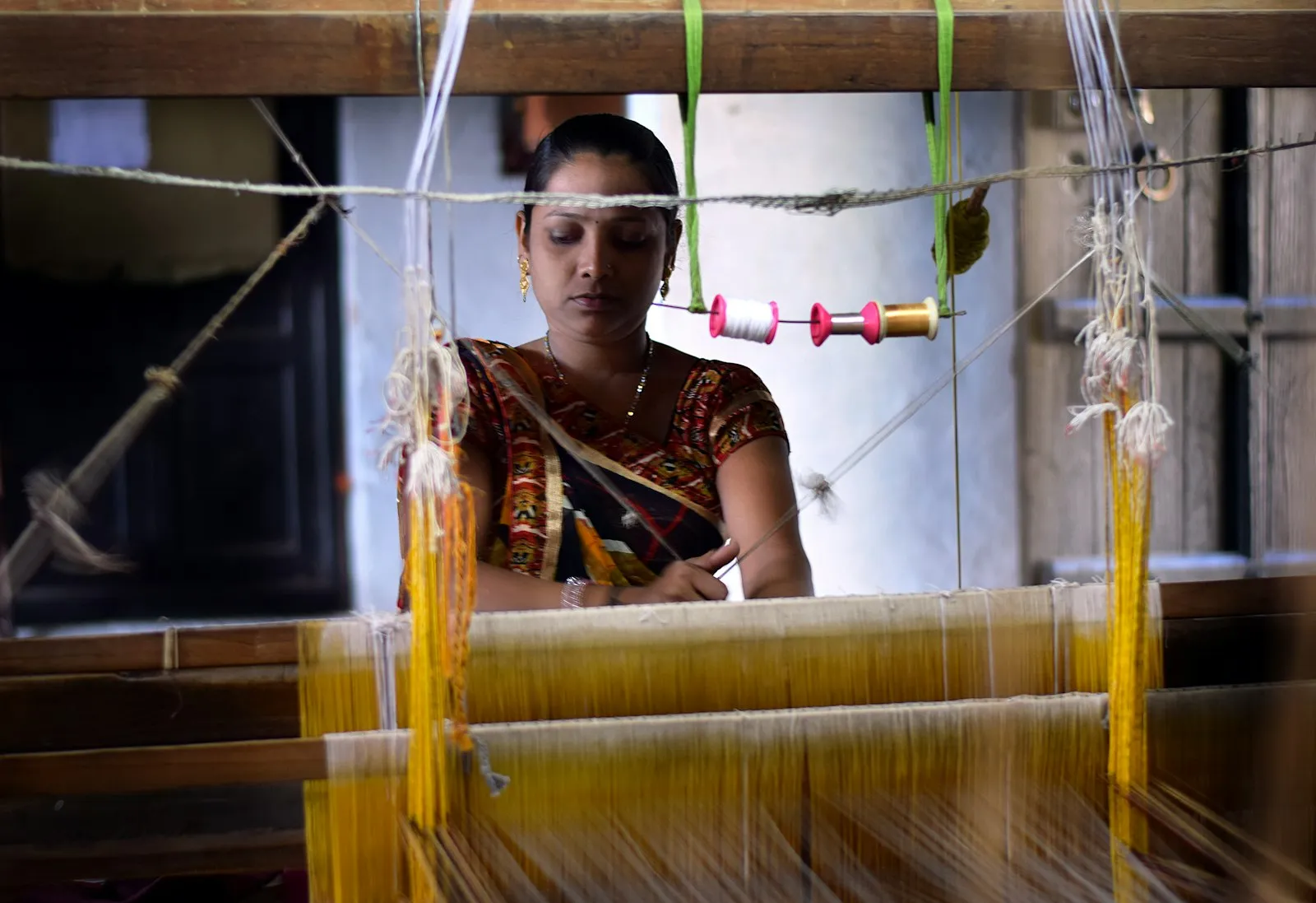 A craftswoman weaving handwoven fabric at a traditional handloom in India