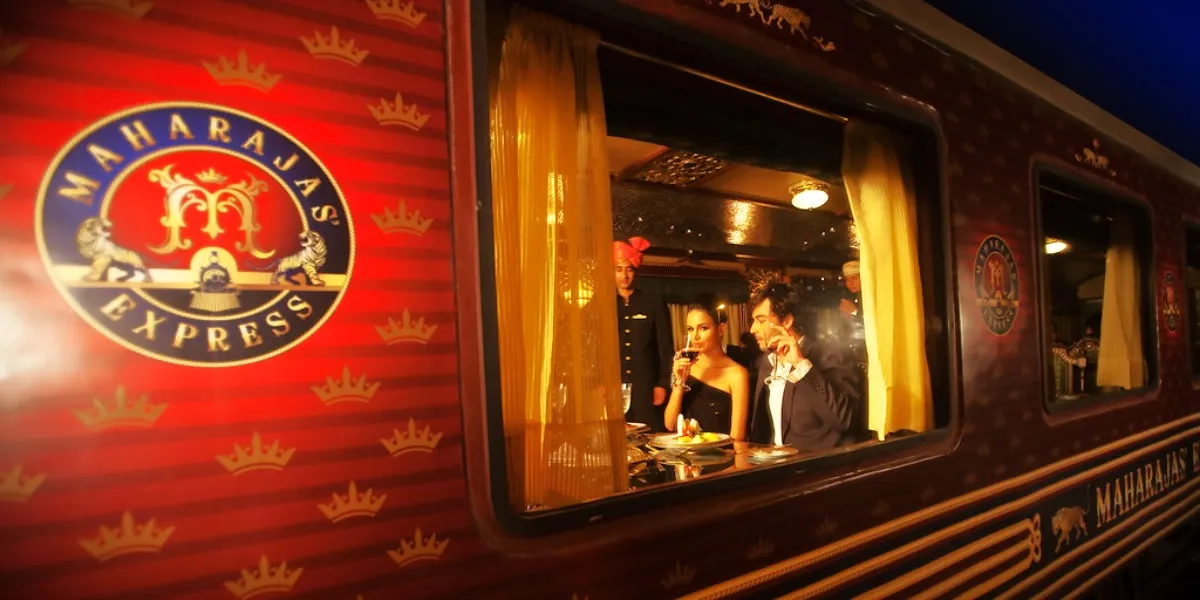 The deep-red and gold carriages of the Maharajas' Express beside a flower-decorated platform at night