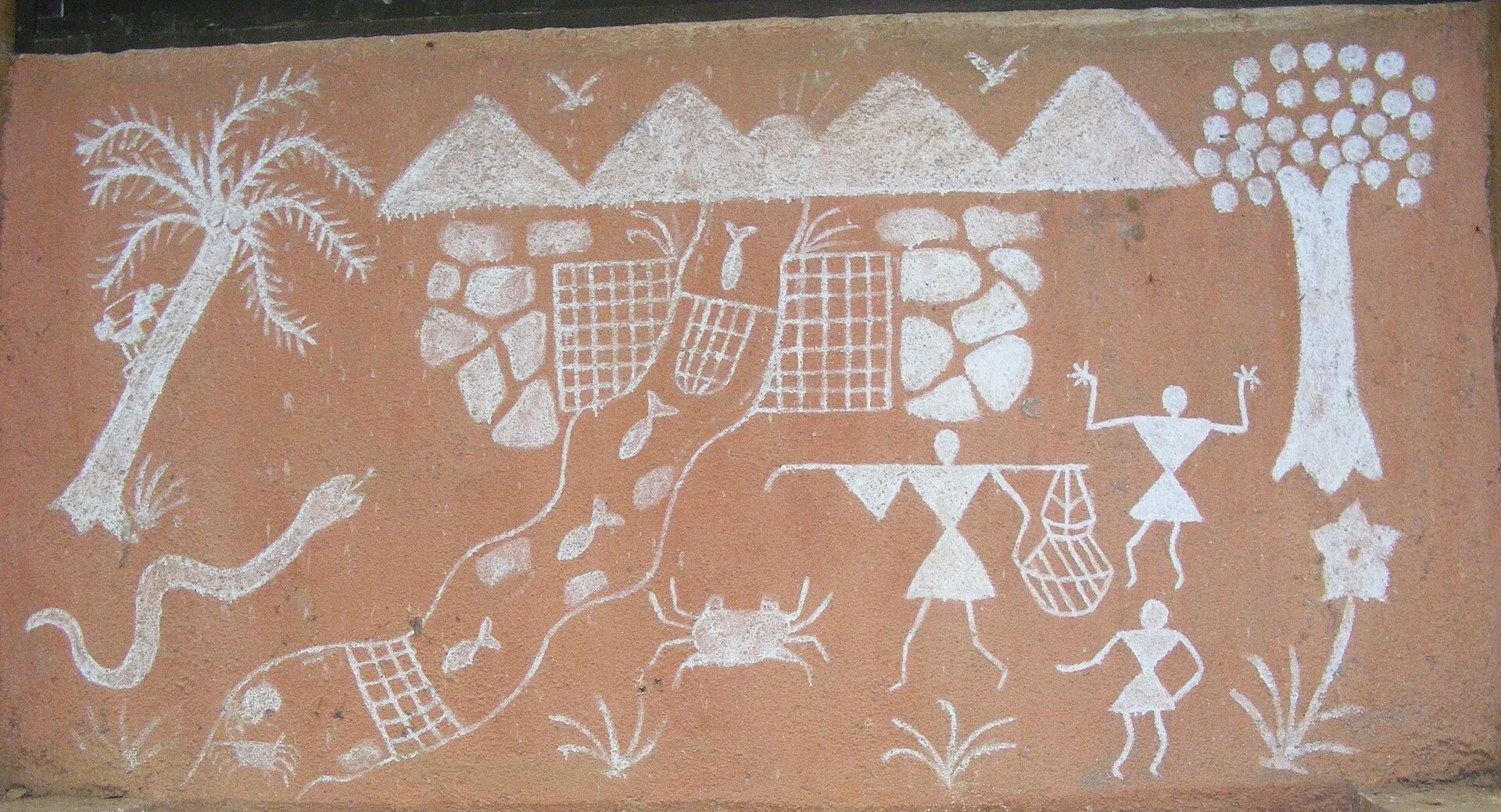 A traditional Warli wall mural in white pigment on an ochre house wall