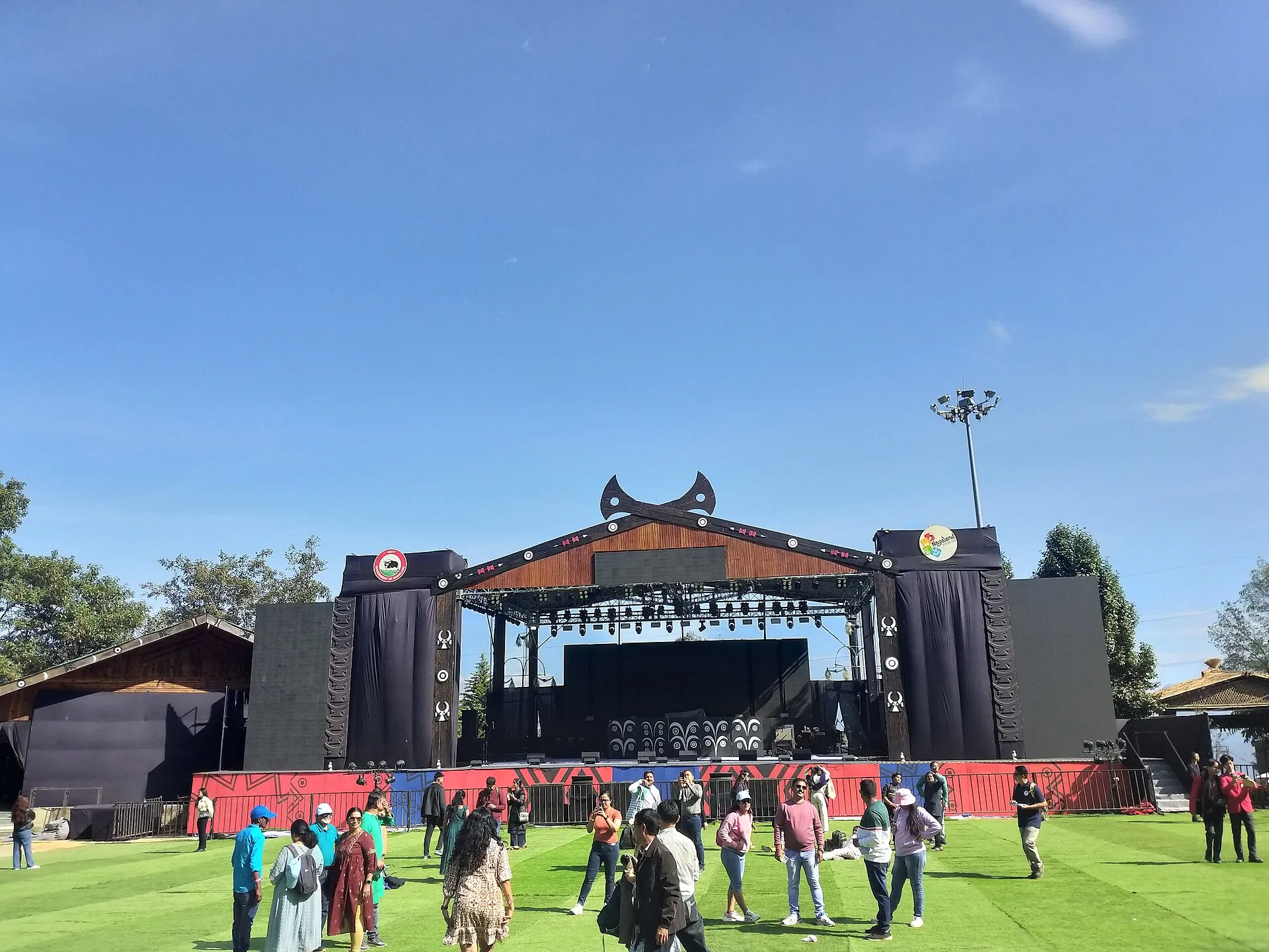 The horned-gable main stage of the Hornbill Festival in Nagaland with festival-goers on the green