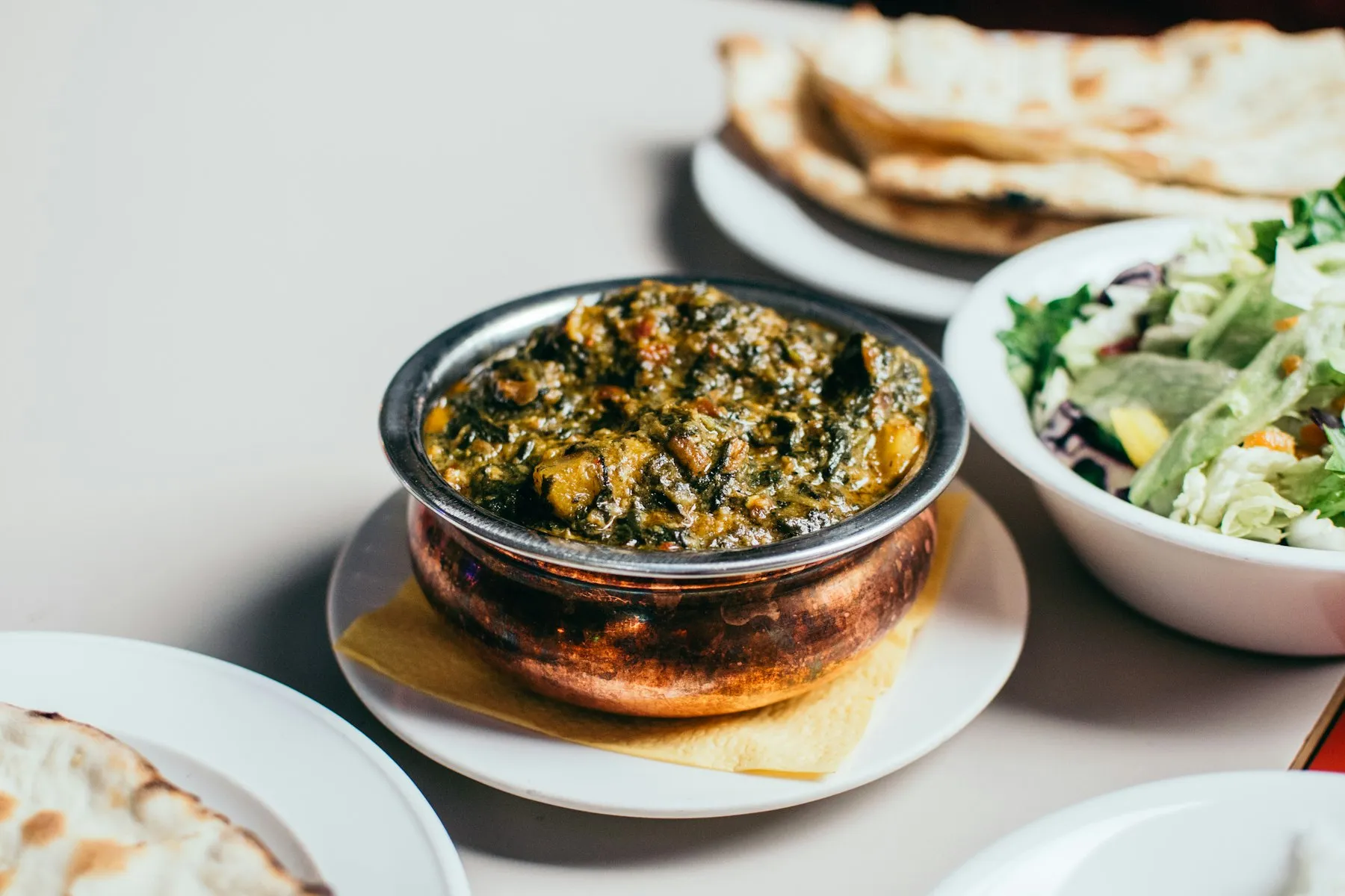 A bowl of sarson da saag served with makki di roti — a Punjabi winter classic