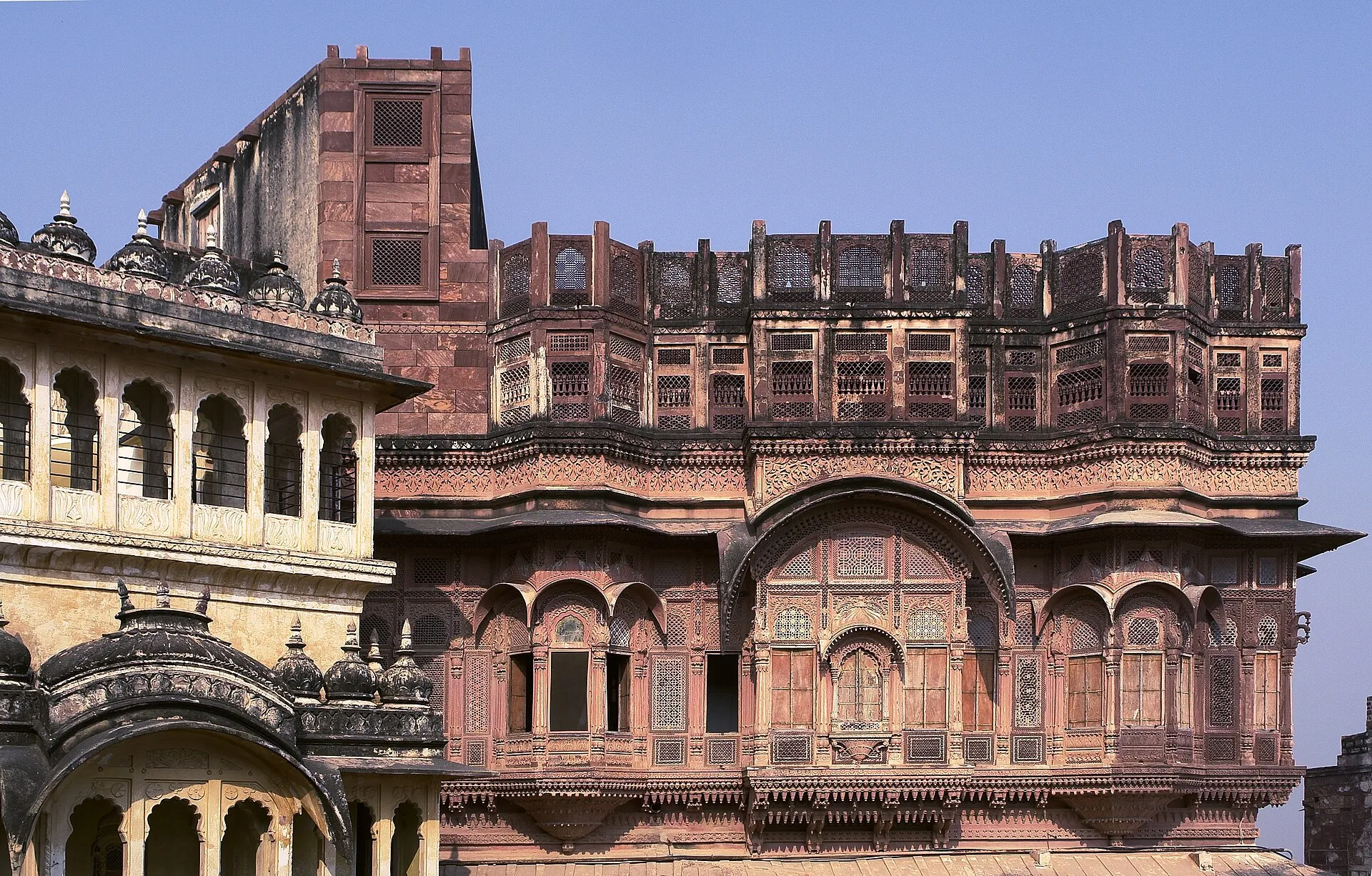 A floodlit Rajasthan fort palace rising above the city at dusk