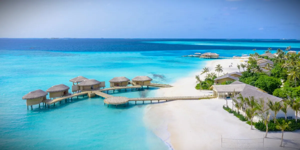 An aerial view of a Maldivian island ringed by a turquoise lagoon and reef